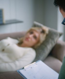 Young patient on the couch talking about her problem to the psychiatrist at therapy. Professional conducts psychological therapy to a young woman in the office